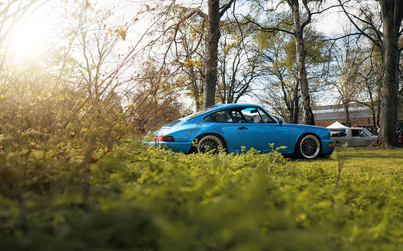 Porsche 911 964 azul sobre pasto, en un encuentro de autos clásicos
